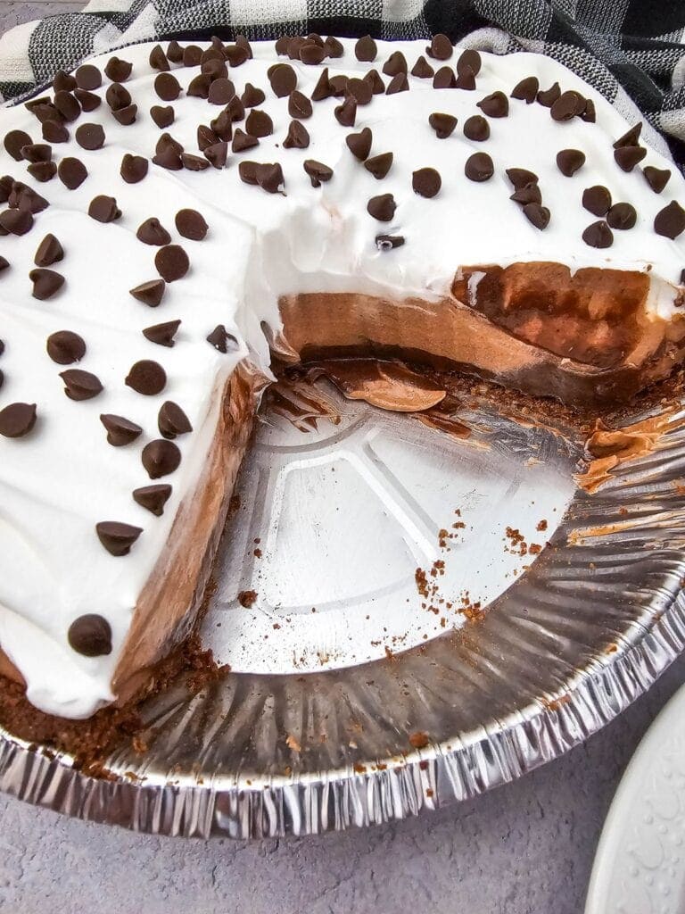 Chocolate pudding pie topped with whipped cream and chocolate chips.