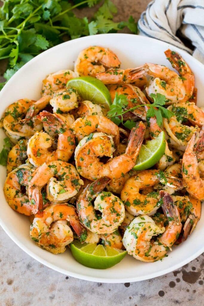 Cilantro lime shrimp in a bowl with lime wedges.