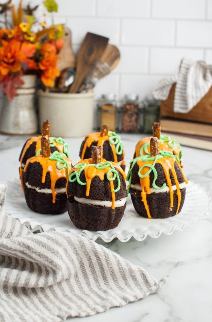 Dark chocolate pumpkin-shaped mini-Bundt cakes on a plate.