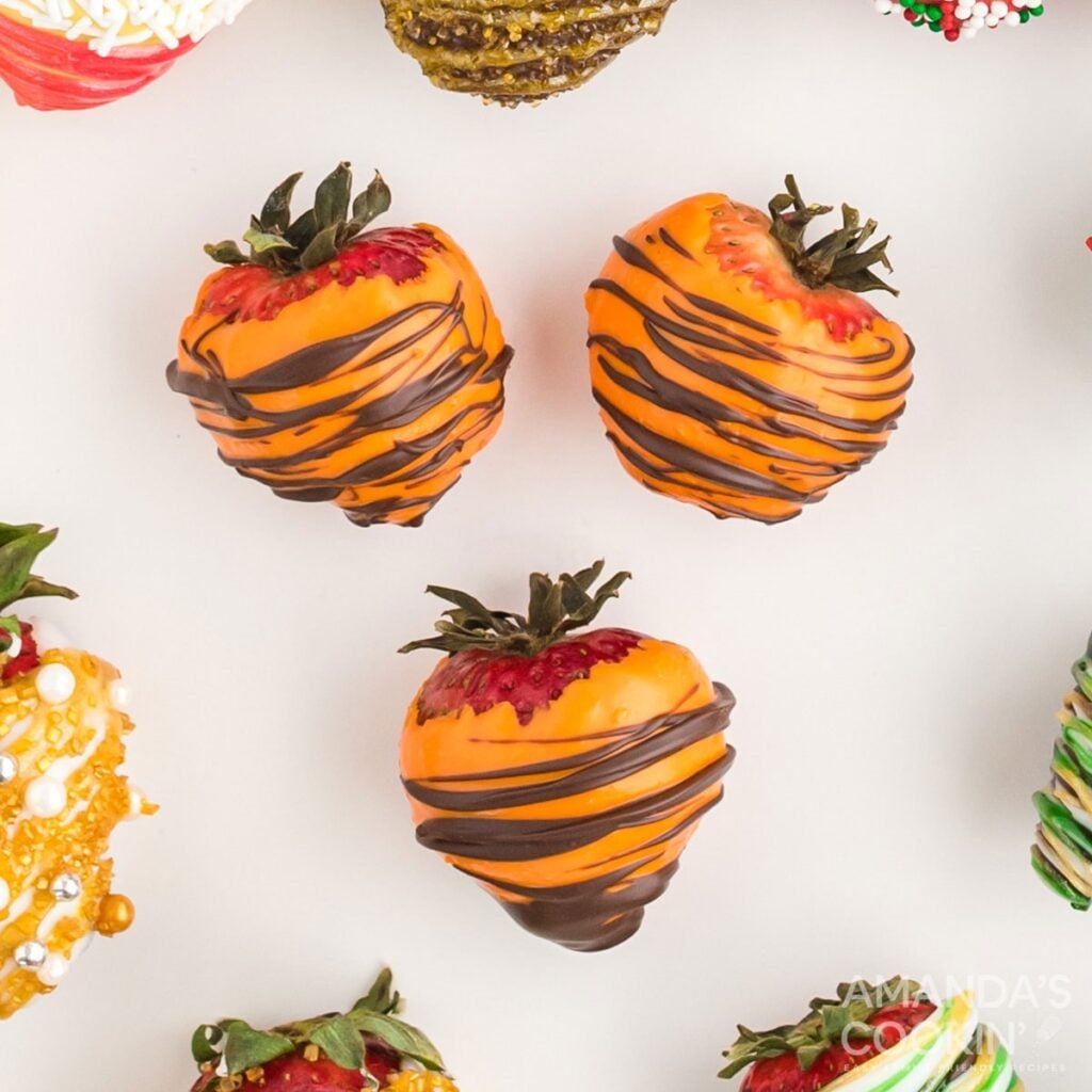 Fall chocolate-covered strawberries on a white surface.