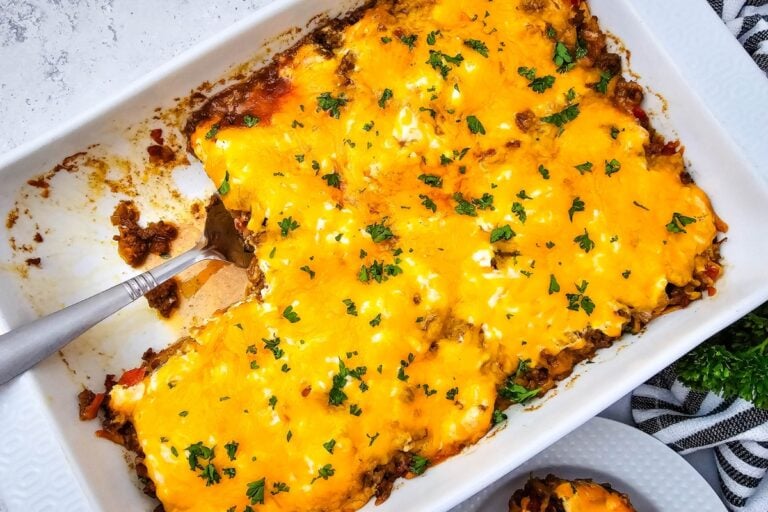 John Wayne Casserole casserole topped with melted cheddar cheese and parsley in a baking dish.