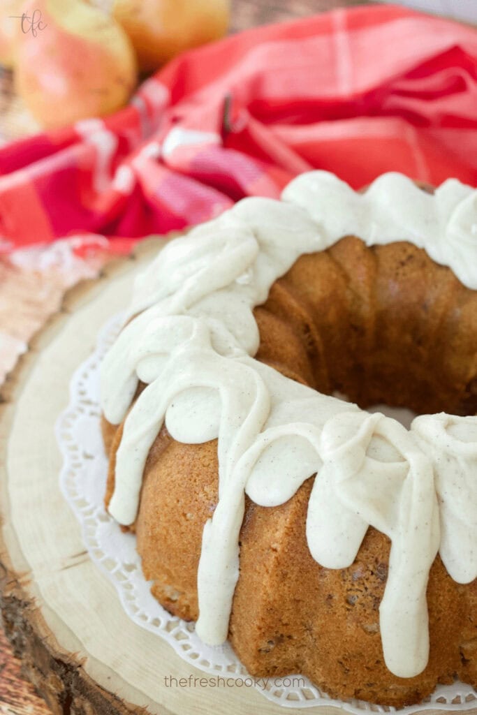 Pear bundt cake with icing on a wooden serving board.