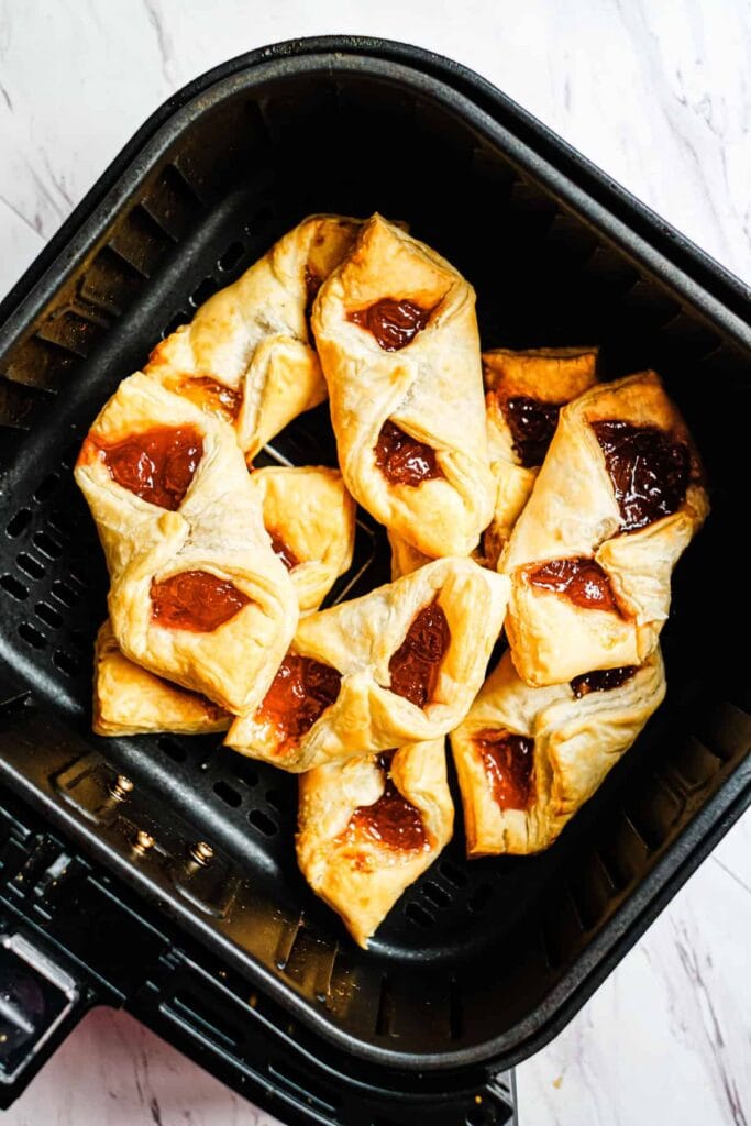 Golden puff pastry breakfast bites in an air fryer basket.