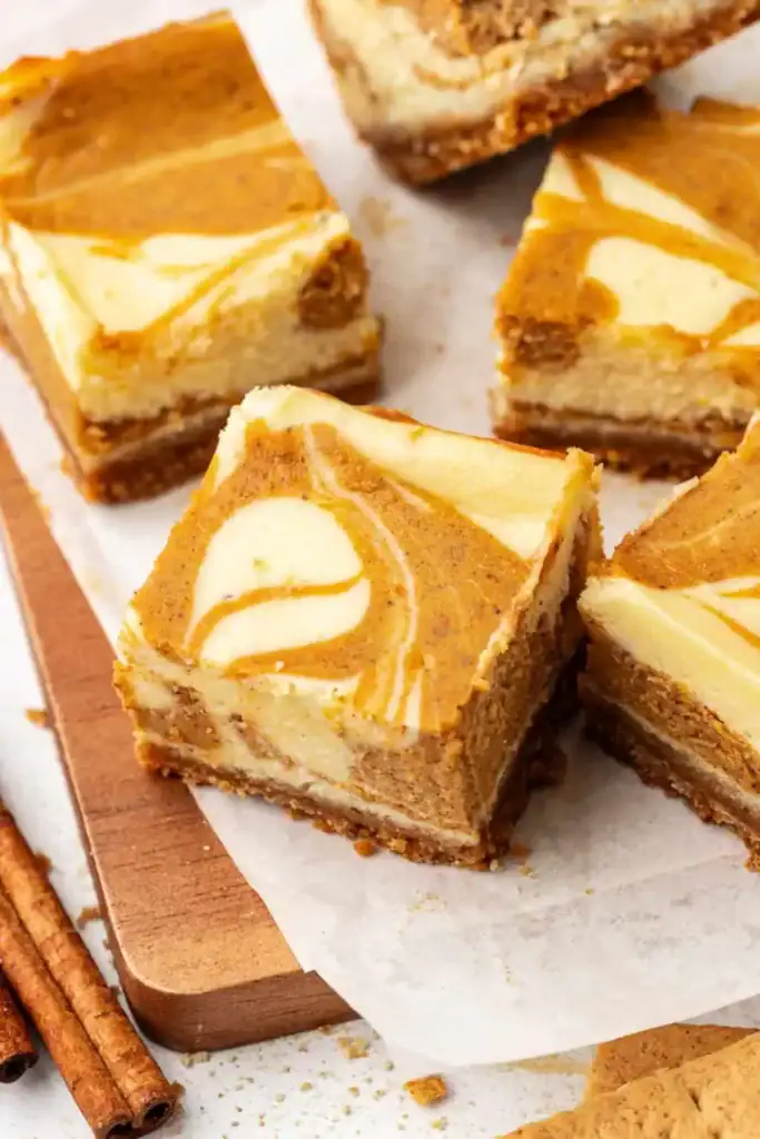 Pumpkin cheesecake bars on a wooden board.