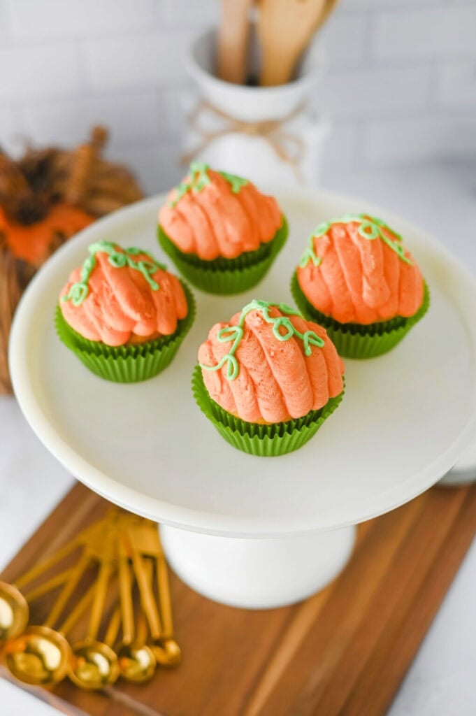 Pumpkin cupcakes on a white cake stand.