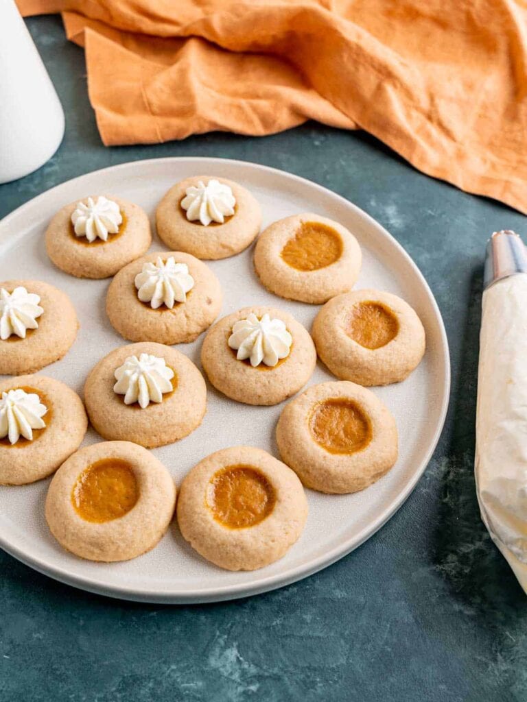 Pumpkin pie filled thumbprint cookies on a plate.