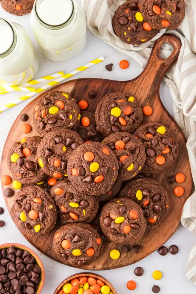Reese's Pieces chocolate cookies on a wooden board.