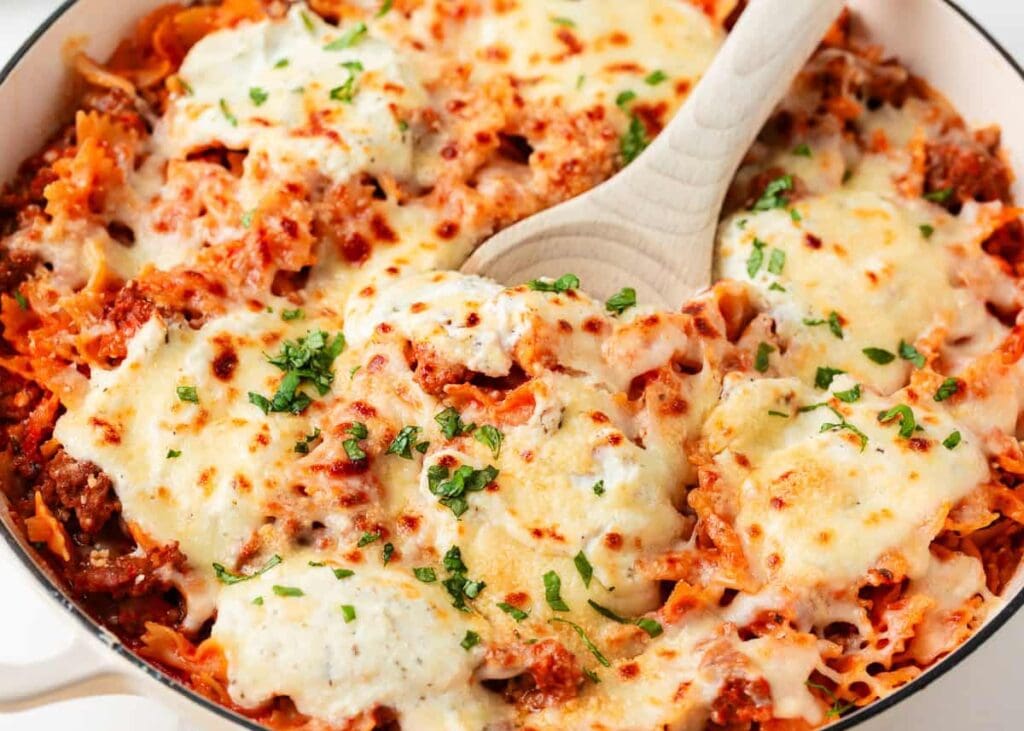 Skillet lasagna with melted cheese on a wooden spoon.