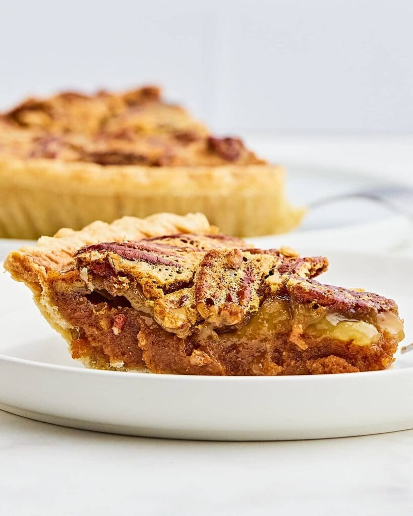 Slice of sweet potato pecan pie on a white plate.