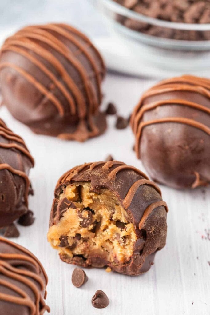 Chocolate-covered cookie dough truffles, one cut open showing cookie dough.