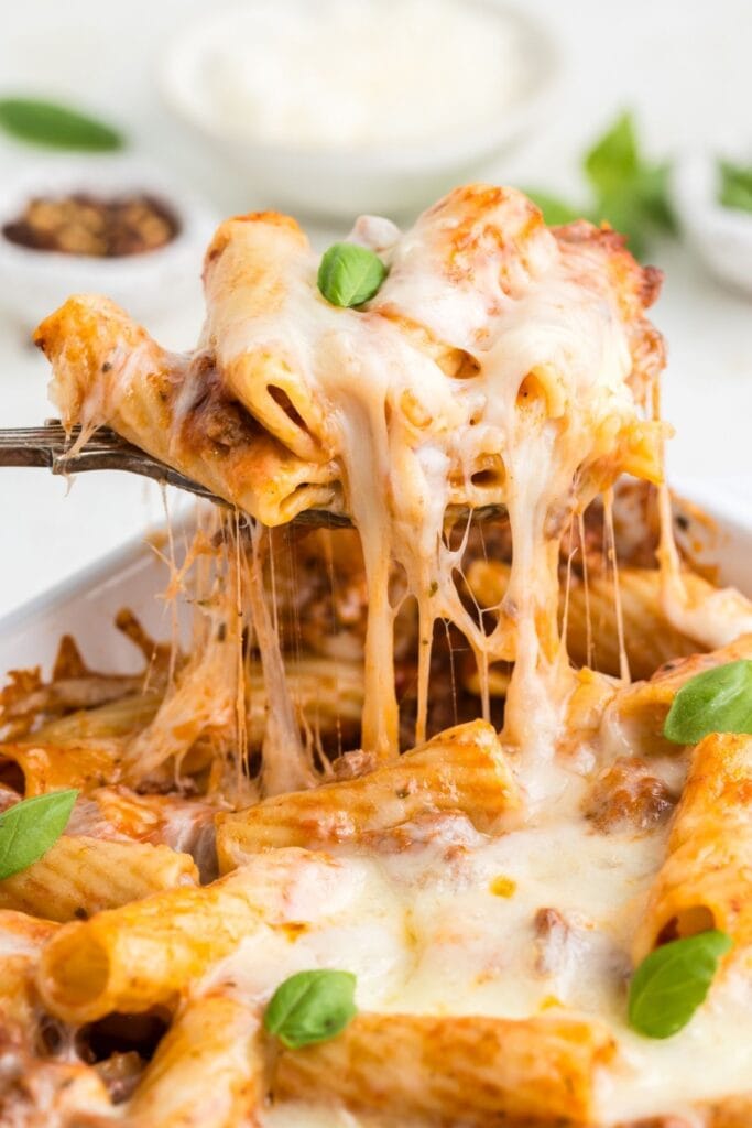 Close-up of cheesy baked rigatoni on a serving spoon.