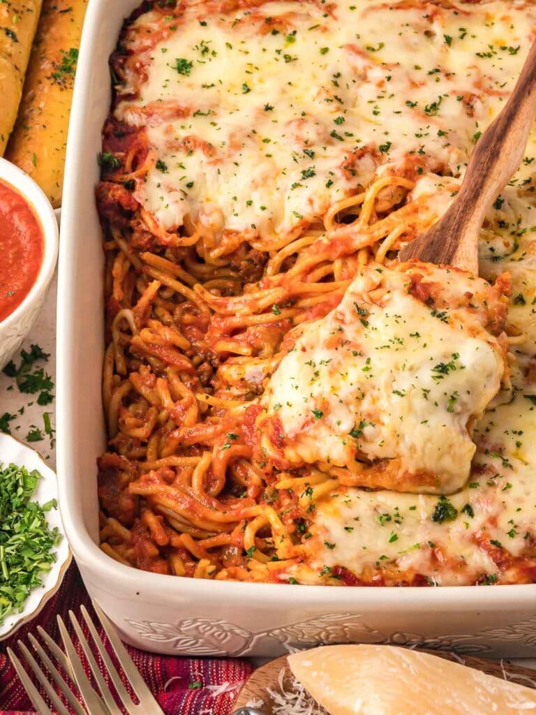 Baked spaghetti in a baking dish with a serving spoon.