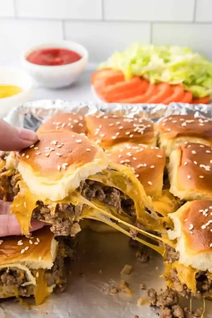 Cheeseburger sliders with a cheesy slider being pulled apart.