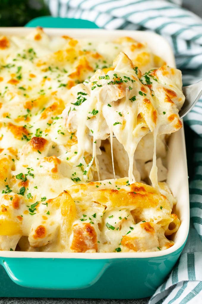 Chicken Alfredo pasta bake in a baking dish with a serving spoon.