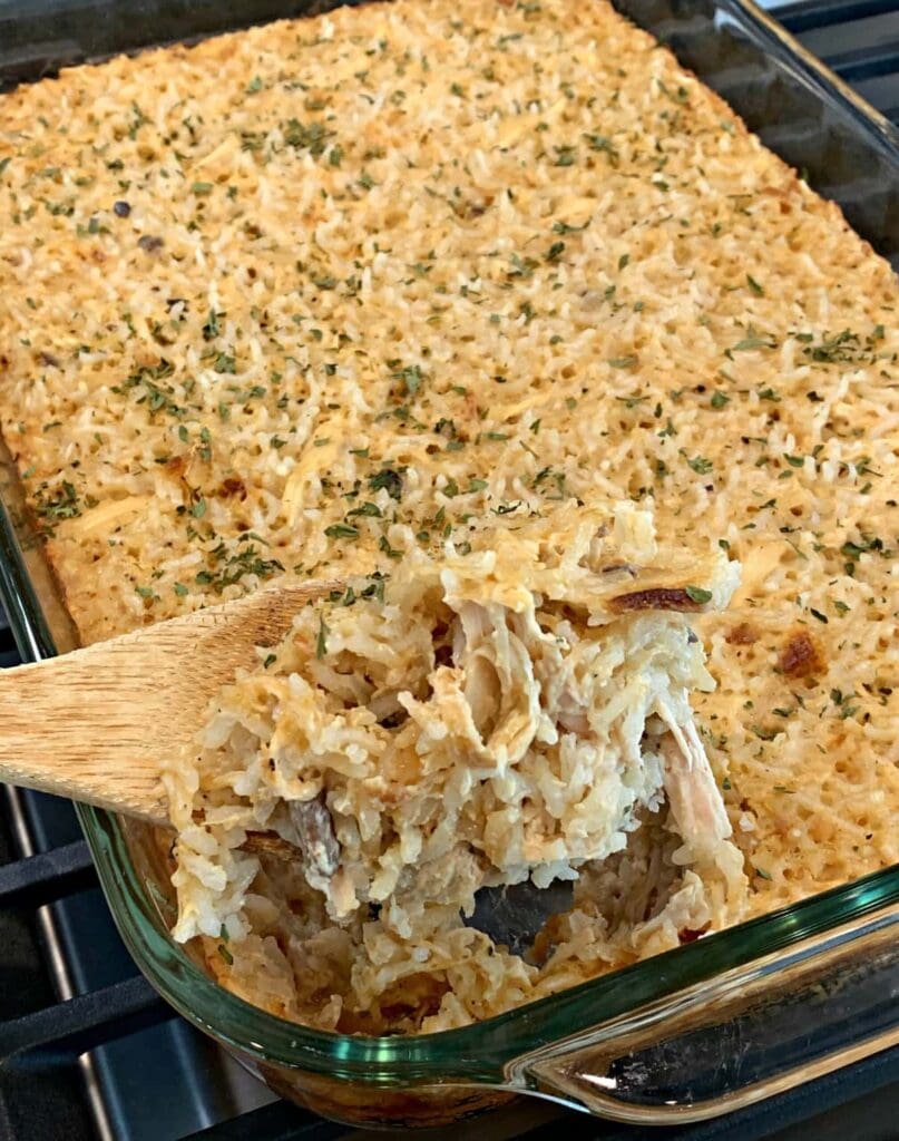 Chicken and rice casserole in a baking dish with a wooden spoon.