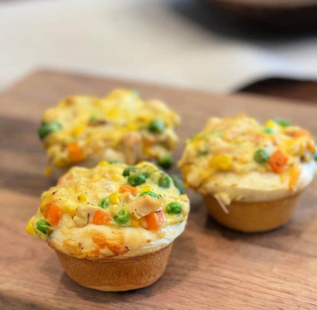 Chicken pot pie muffins on a wooden board.