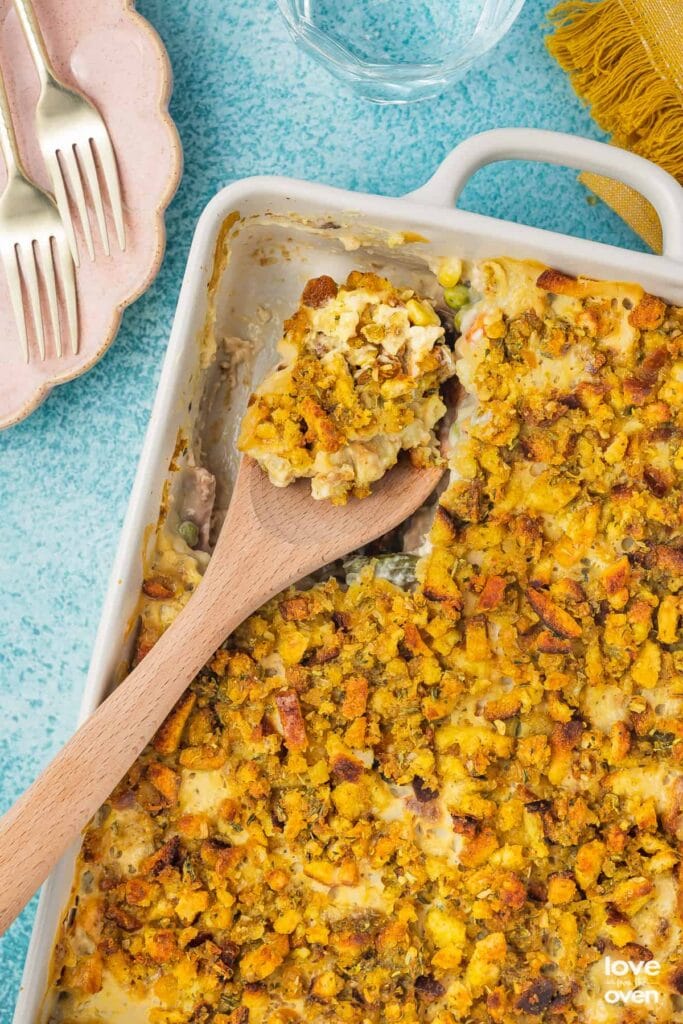 Chicken stuffing casserole in a white baking dish with a wooden spoon.