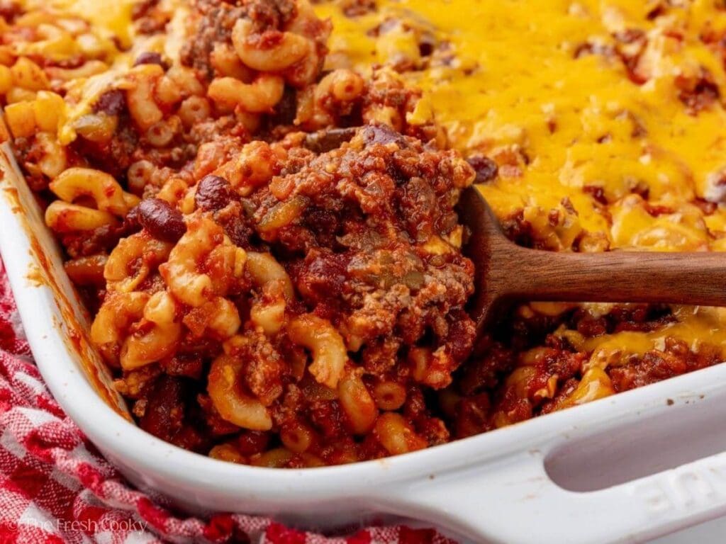Chili mac casserole in a baking dish with a wooden spoon.