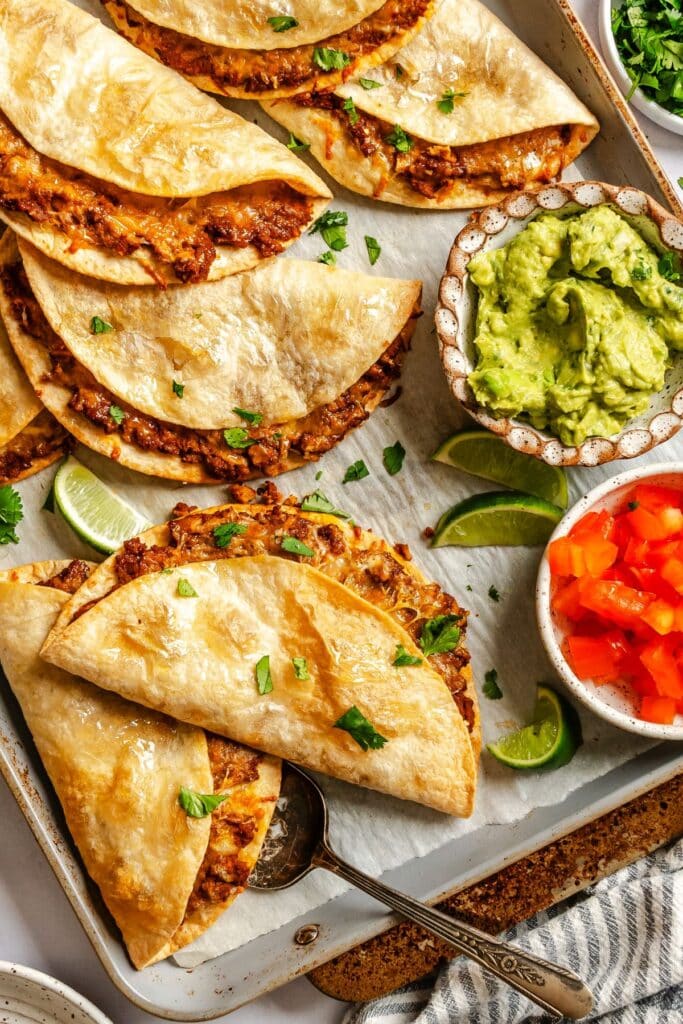 Crispy baked tacos on a baking sheet.