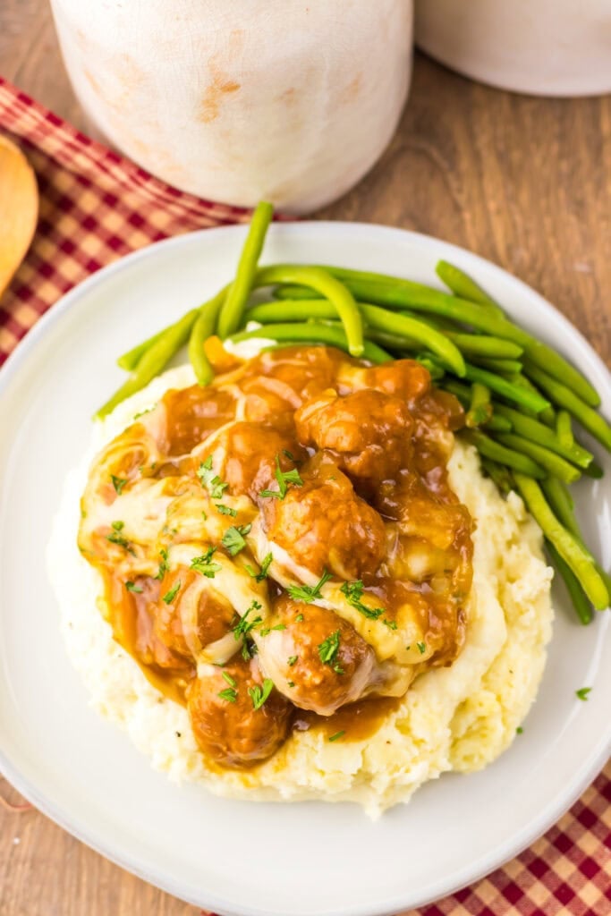 Overhead shot of French onion meatballs with mashed potatoes on a plate.