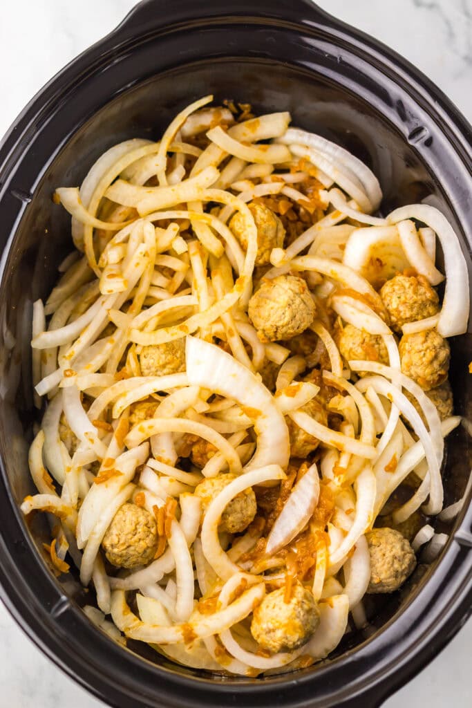 Onions and meatballs in a slow cooker.