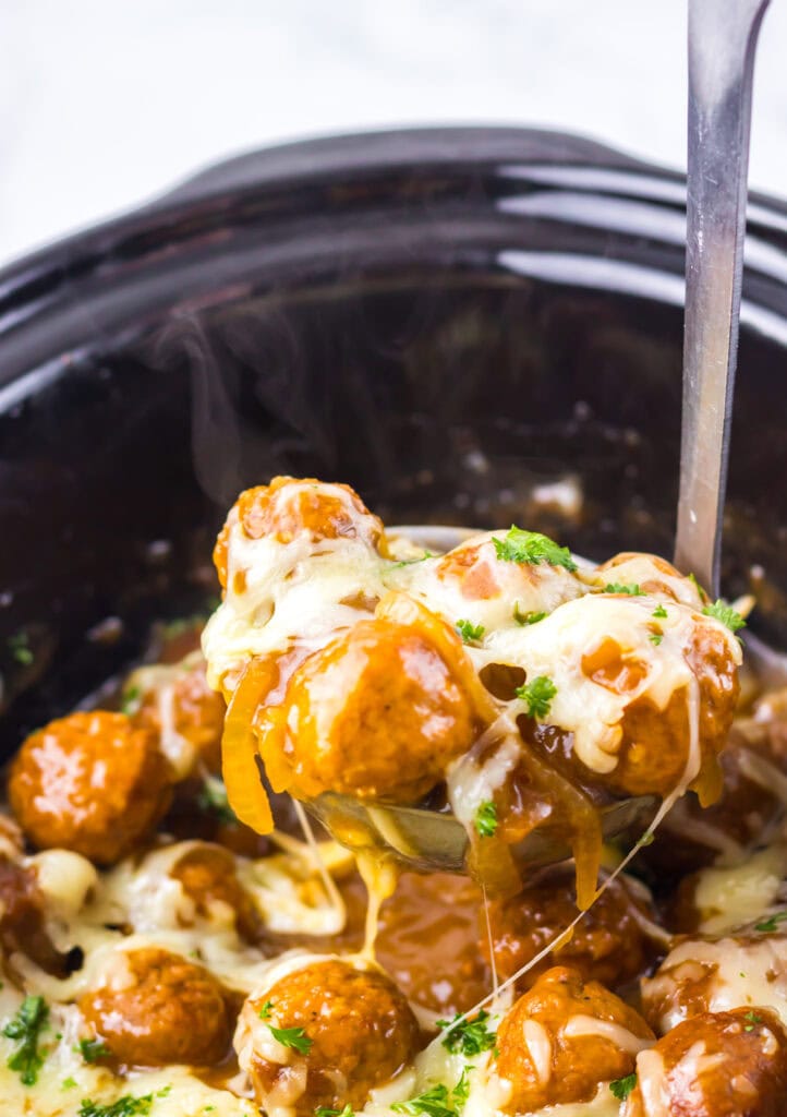 Saucy meatballs with melted cheese in a slow cooker.