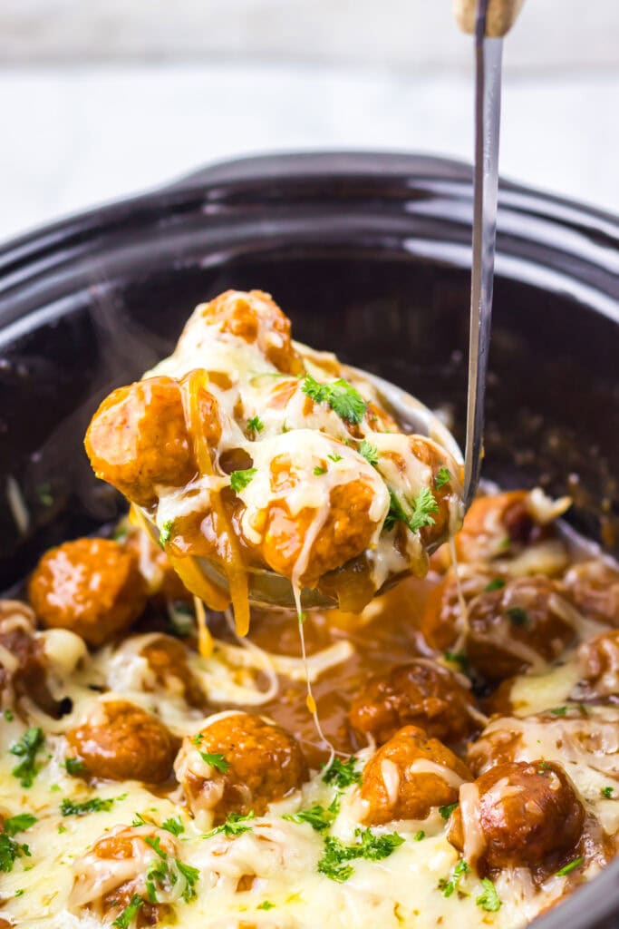 Saucy meatballs with melted cheese in a slow cooker.