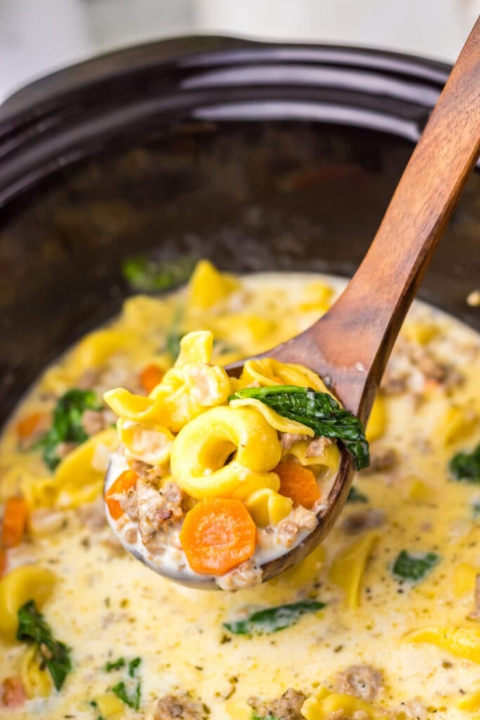 Crockpot tortellini soup on a wooden spoon.