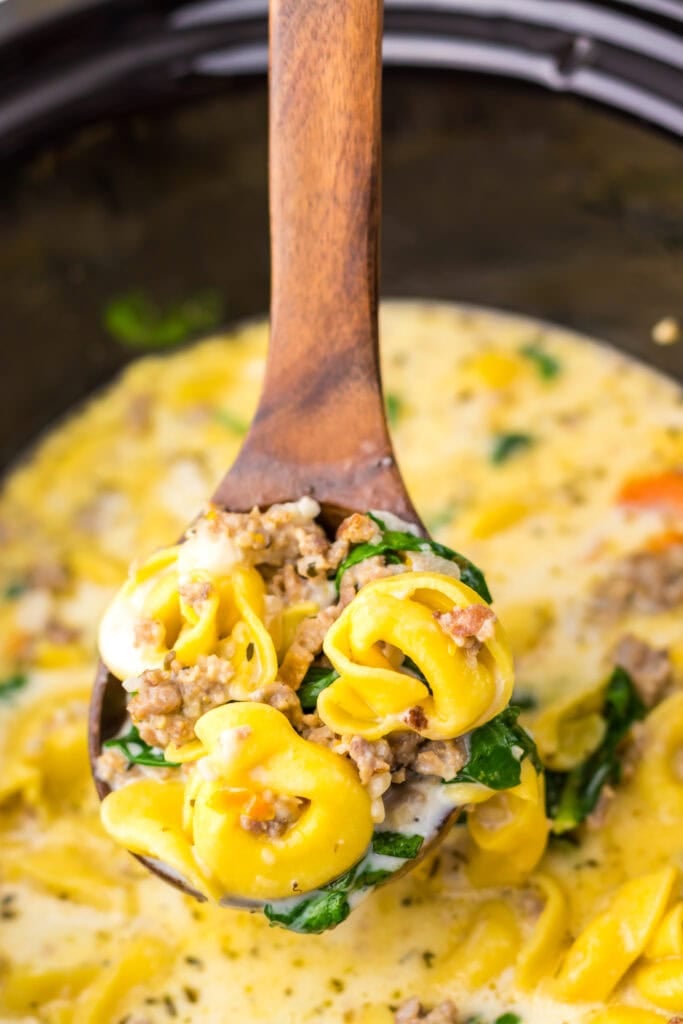 Crockpot tortellini soup on a wooden spoon.