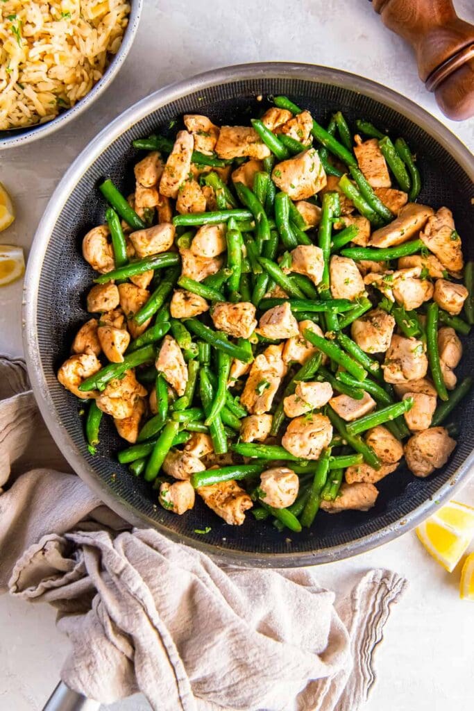 Garlic butter chicken and green beans in a skillet.