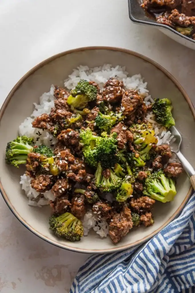 Ground beef and broccoli served over rice on a plate.