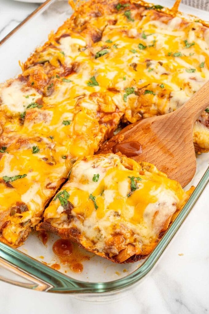 Lazy enchiladas in a baking dish with a wooden spatula.