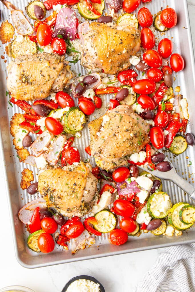 Mediterranean Sheet Pan Chicken on a baking sheet in an overhead view.
