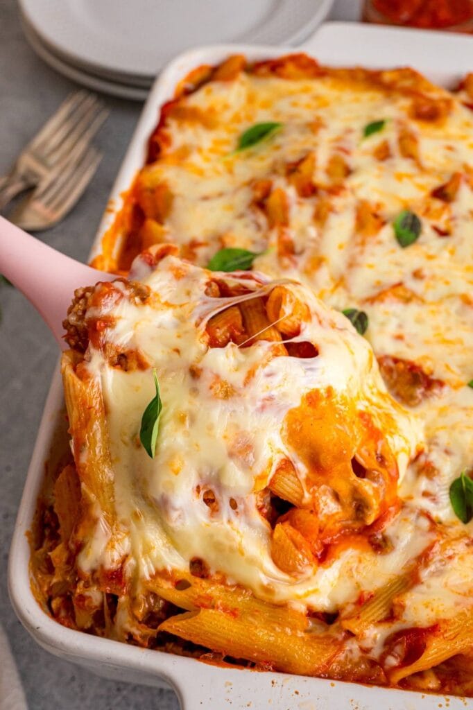 Cheesy mostaccioli casserole with a serving spoon.