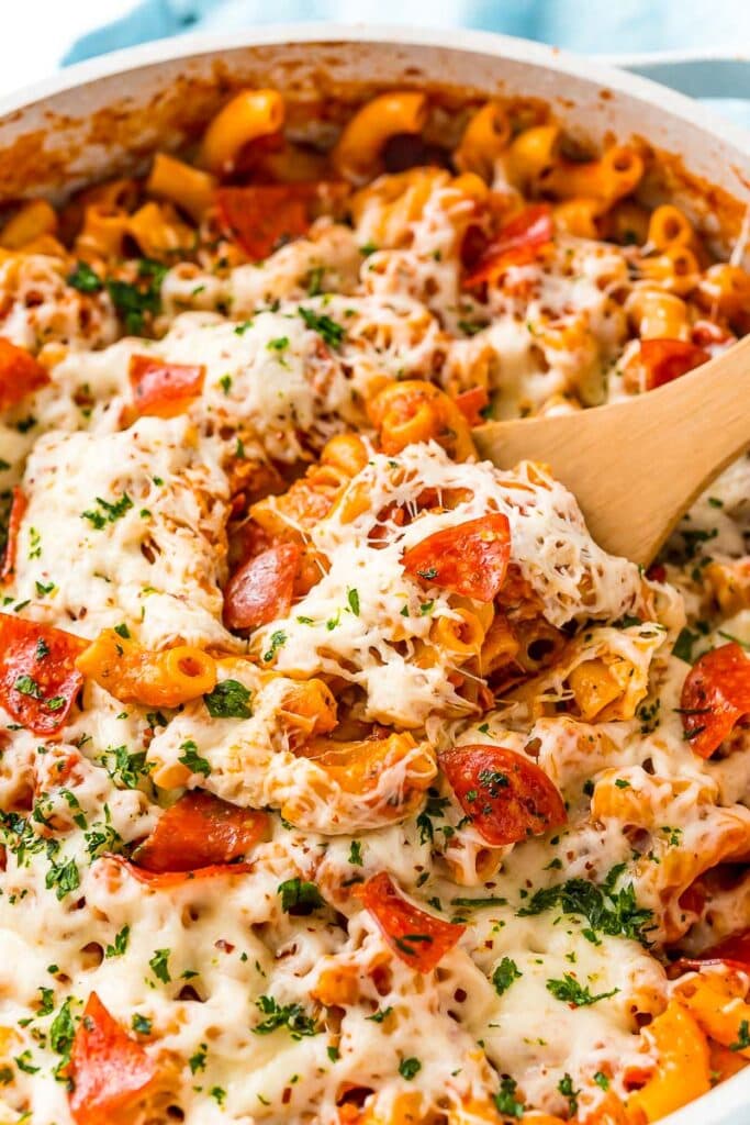 One pan pizza pasta with a wooden spoon.