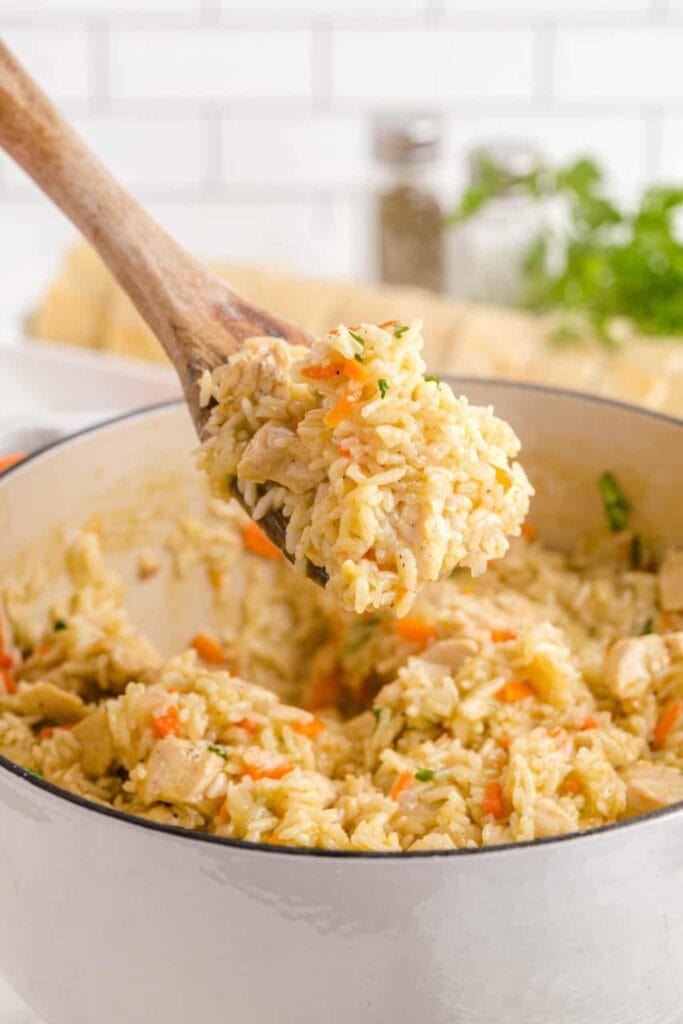 Close-up of one pot chicken and rice on a wooden spoon.