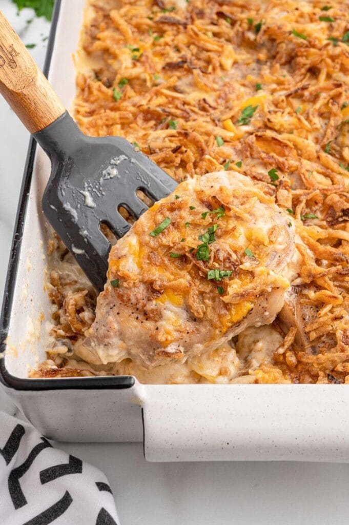Pork chop casserole in a baking dish with a serving spatula.