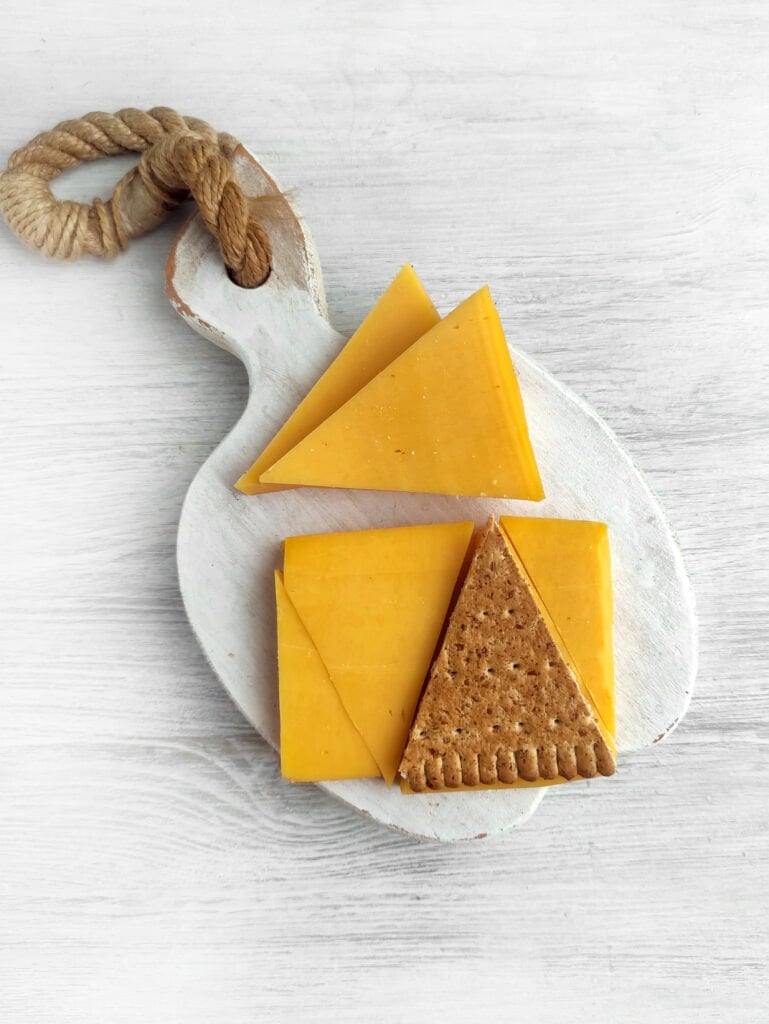 Cheese cut into triangles on a white board.