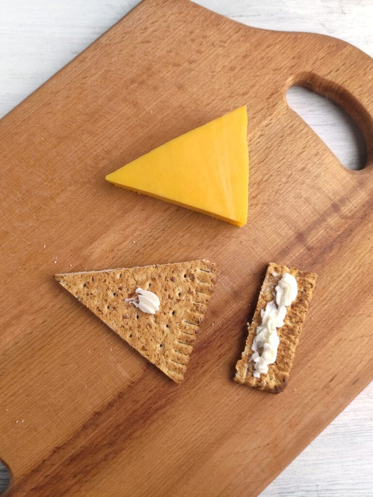 Piping cream cheese onto a cracker.
