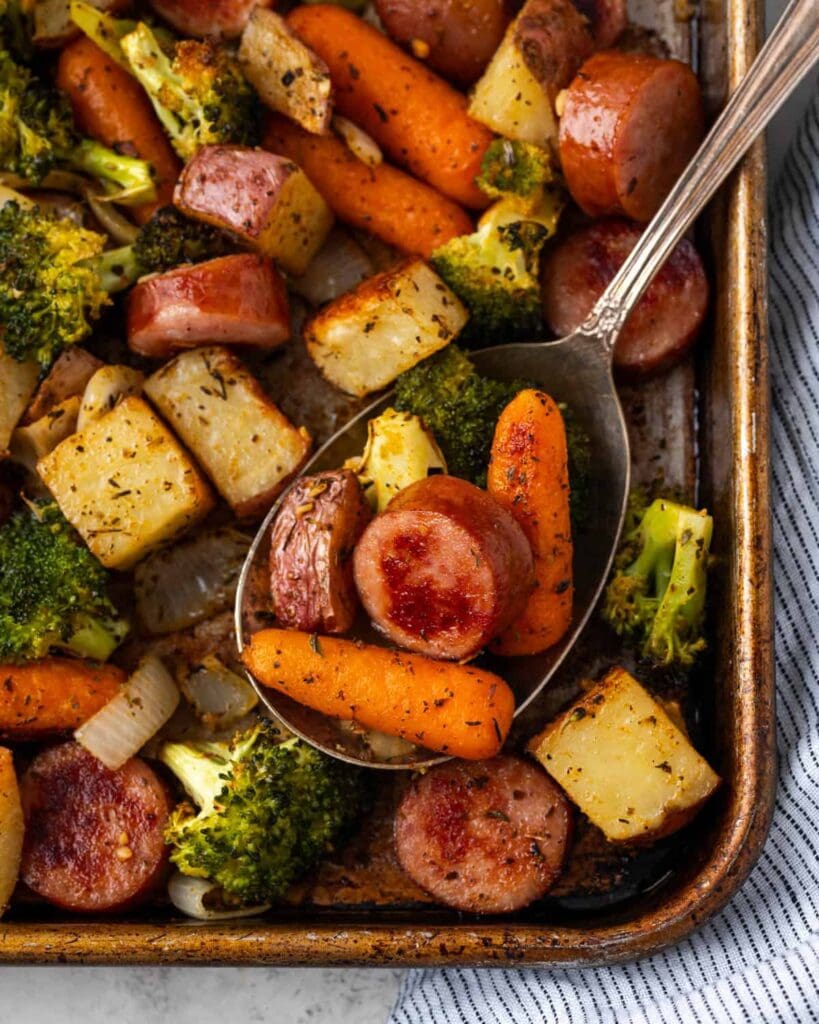 Sausage and Vegetable Sheet Pan Dinner with a serving spoon.