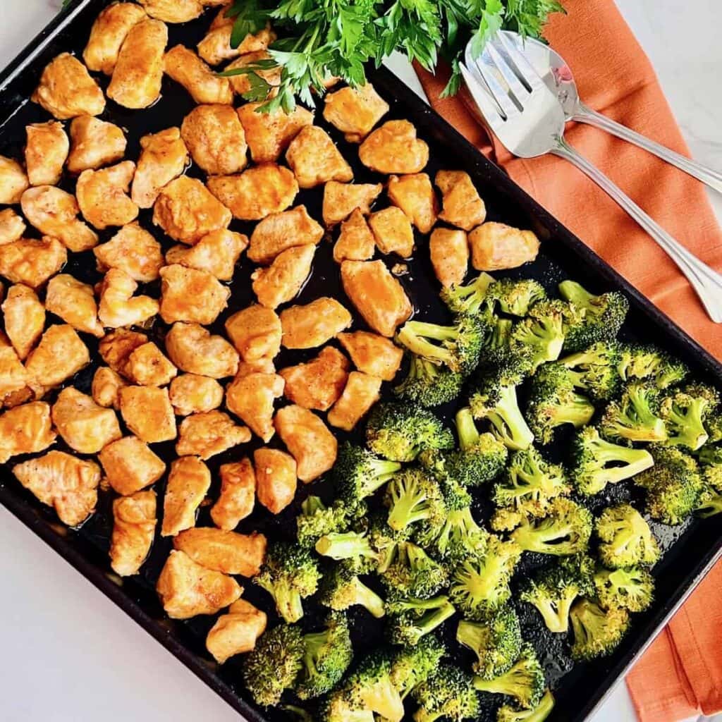 Roasted buffalo chicken bites and broccoli on a sheet pan.