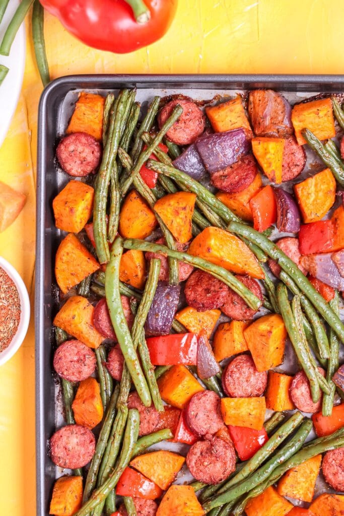 Roasted Cajun sausage and sweet potatoes on a sheet pan.