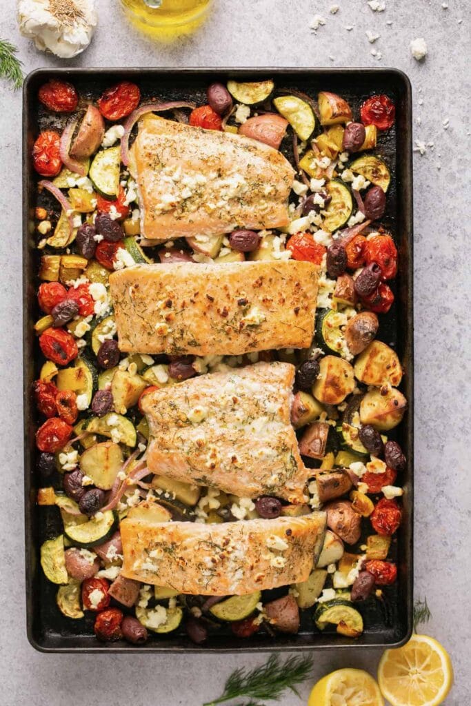 Greek Salmon and Veggies on a baking sheet in an overhead view.