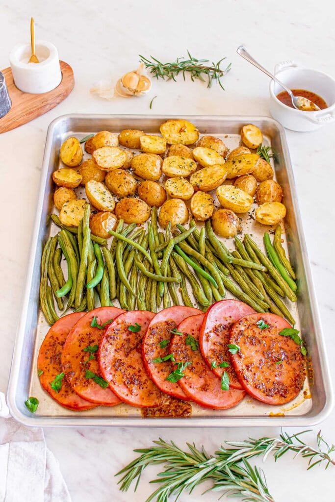 Ham Dinner with roasted potatoes and green beans on a baking sheet in an overhead view.