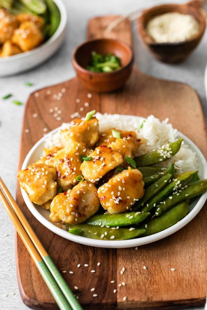 Orange chicken with rice and snap peas in a bowl.