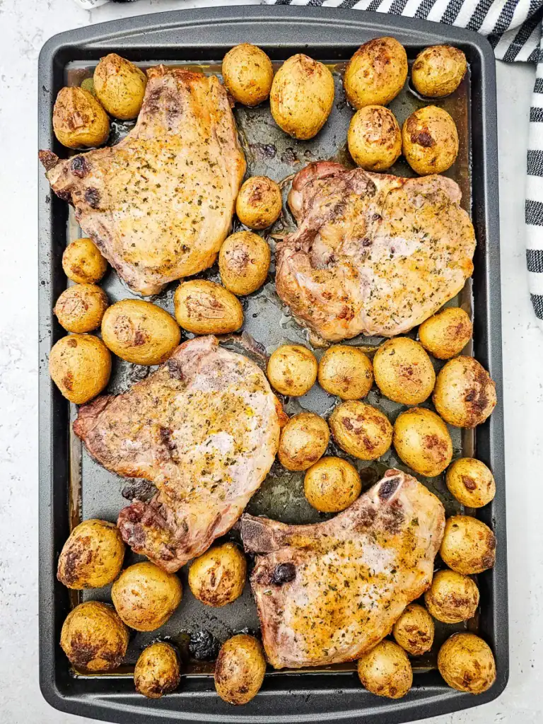 Roasted pork chops and potatoes on a sheet pan.