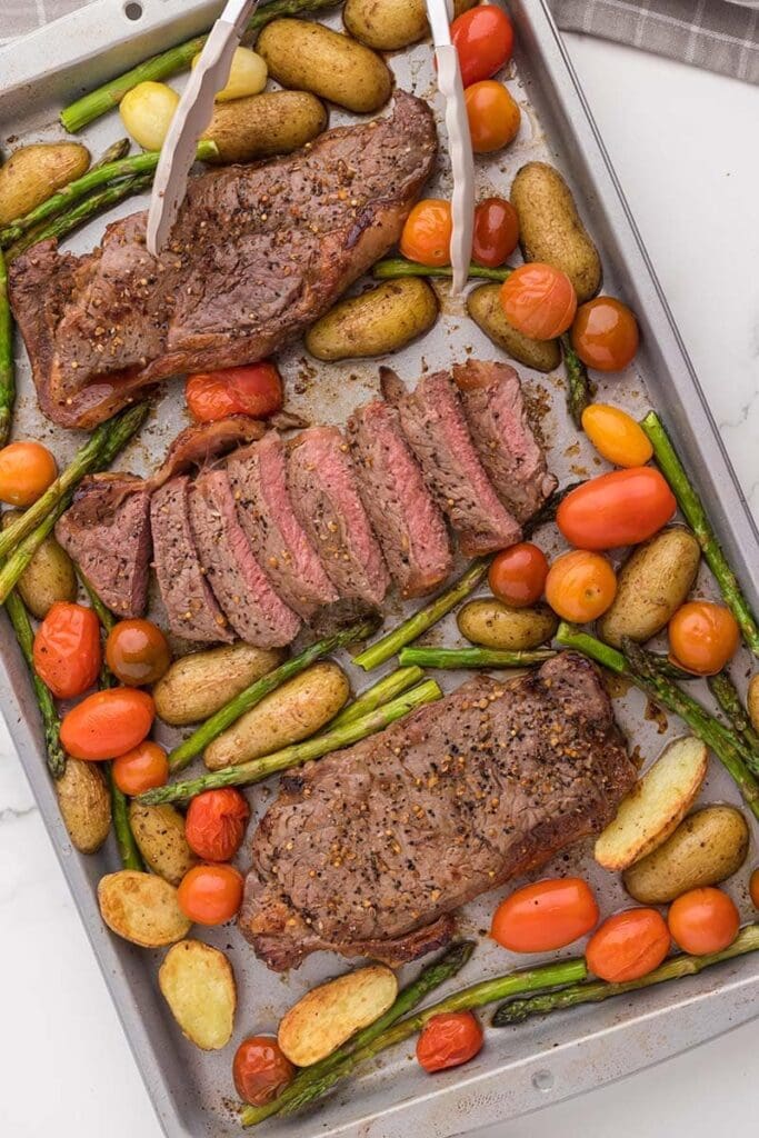 Steak and vegetables on a sheet pan.