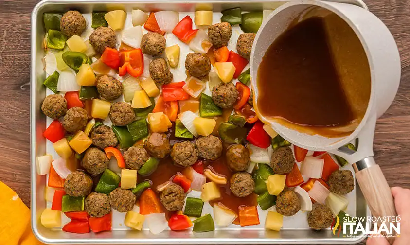 Sweet and Sour Meatballs with vegetables and sauce being poured over the top.