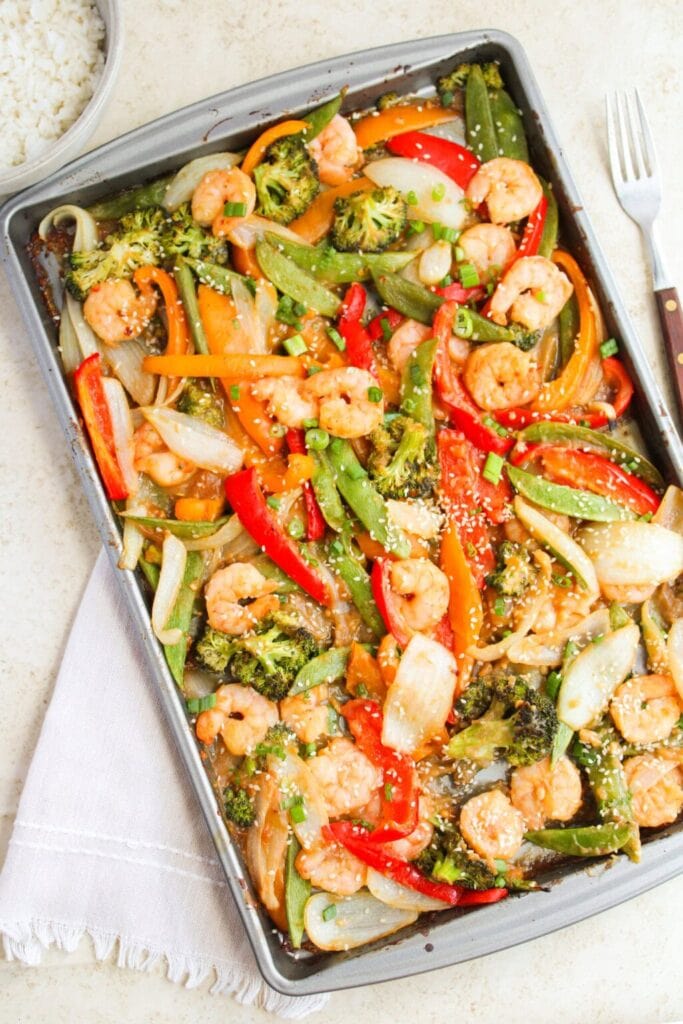Shrimp and vegetable stir-fry on a baking sheet in an overhead view.