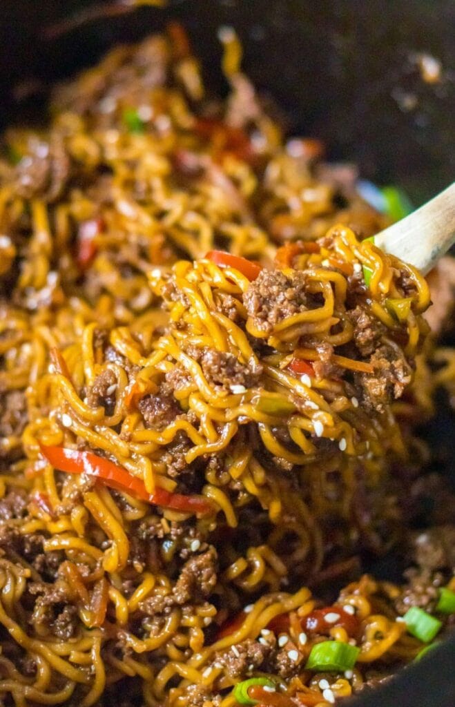 Close-up of slow cooker beef ramen noodles on a serving wooden spoon.